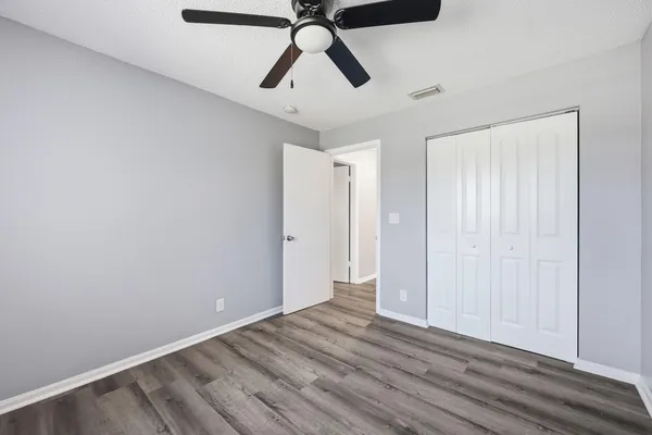 a view of empty room with wooden floor and ceiling fan