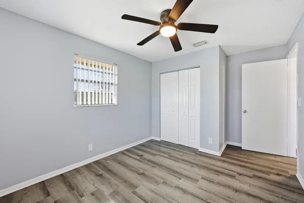 a view of empty room with wooden floor and fan
