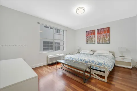 a spacious bedroom with a bed and wooden floor