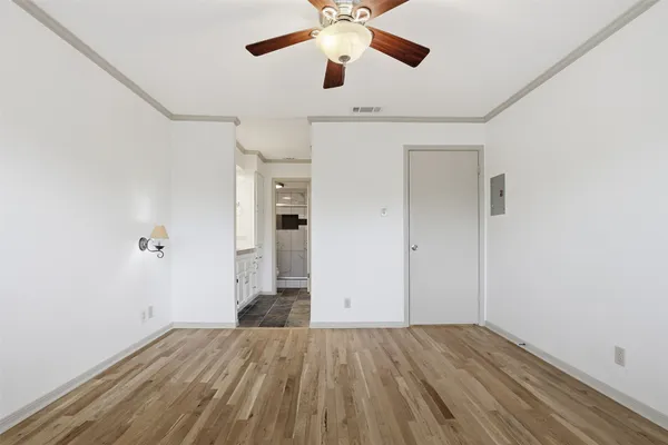 an empty room with wooden floor ceiling fan and windows
