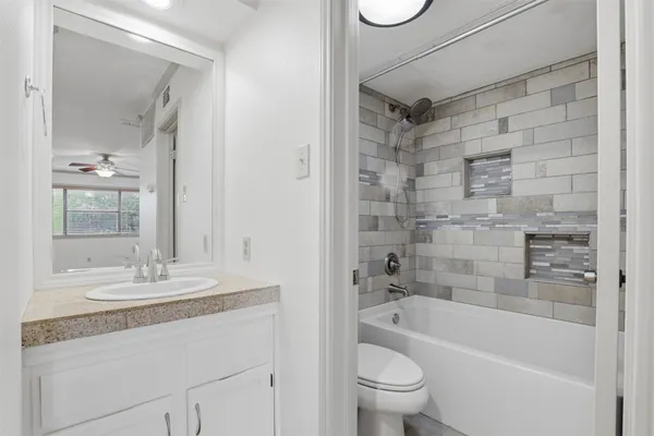 a bathroom with a granite countertop sink a toilet and shower
