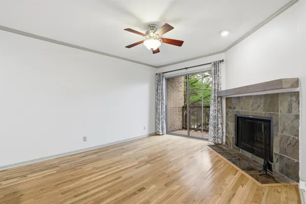 a view of an empty room with wooden floor fireplace and a window