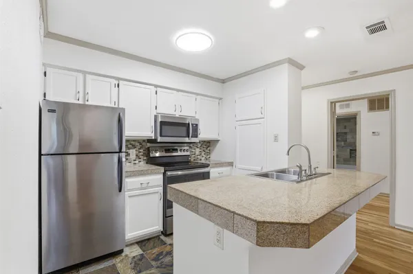 a kitchen with stainless steel appliances granite countertop a sink a stove a refrigerator a washer and dryer