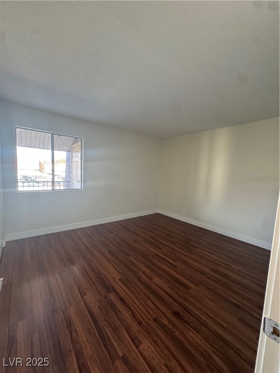 5188 River Glen Drive, Unit 458 Las Vegas, NV 89103 - Photo 6 of 13 Unfurnished room with dark wood-type flooring and a textured ceiling
