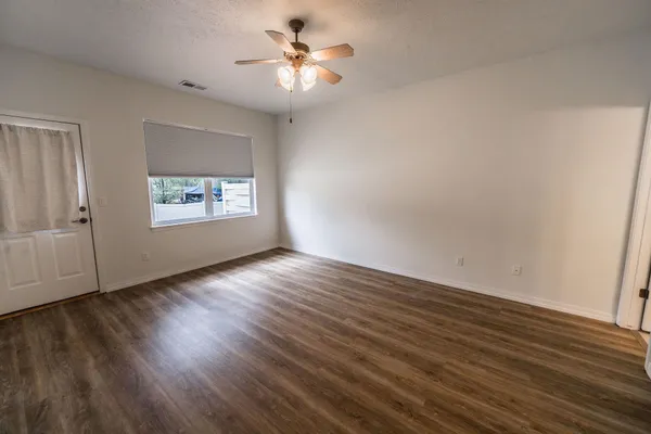 a view of an empty room with a window and wooden floor