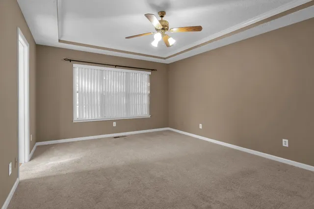 an empty room with windows and fan