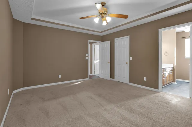 a view of an empty room and chandelier fan