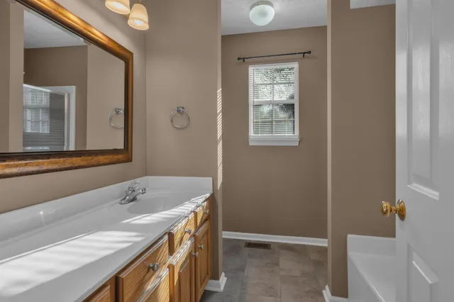 a bathroom with a tub sink and mirror