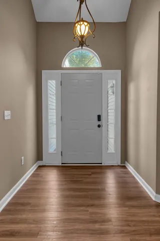 an empty room with wooden floor chandelier fan and windows
