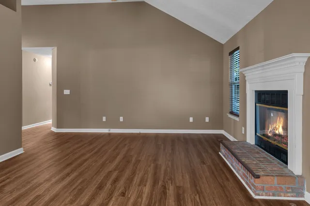 a view of an empty room with wooden floor fire place and a fireplace