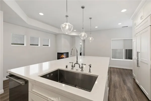 a kitchen with a sink chandelier and wooden floor