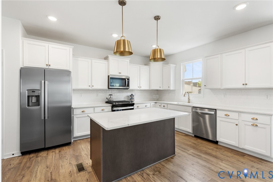 10001 Craftsbury Drive Midlothian, VA 23112 - Photo 15 of 32 a kitchen with stainless steel appliances granite countertop a refrigerator a sink dishwasher a stove and white cabinets with wooden floor