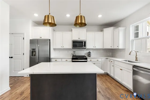 a kitchen with stainless steel appliances a sink a stove a refrigerator and cabinets