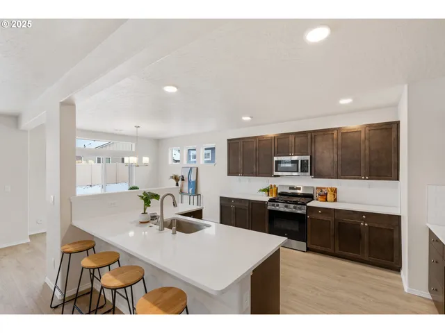 a kitchen with stainless steel appliances kitchen island granite countertop a sink dishwasher stove top oven and cabinets with wooden floor