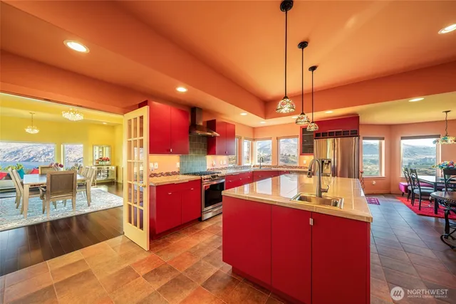 a large kitchen with kitchen island a large counter top a stove and a chandelier