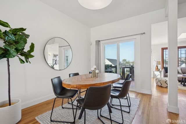 a dining room with furniture a potted plant and wooden floor