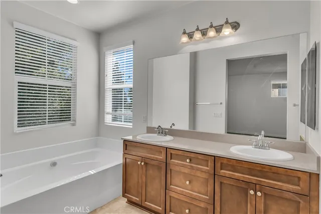 a bathroom with a tub double sink window and mirror