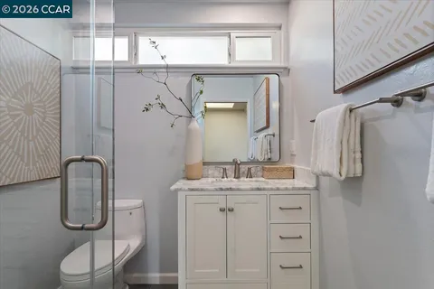 a bathroom with a granite countertop sink toilet a mirror and shower