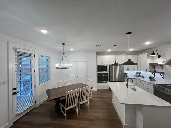 a kitchen with a dining table chairs wooden floor and appliances