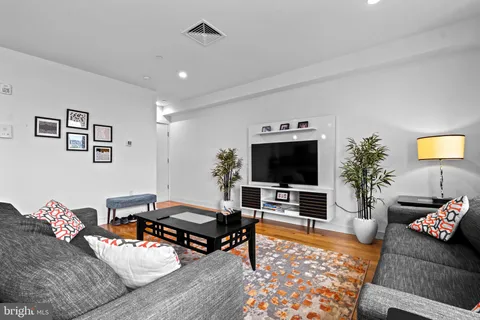 a living room with furniture and a dining table with wooden floor