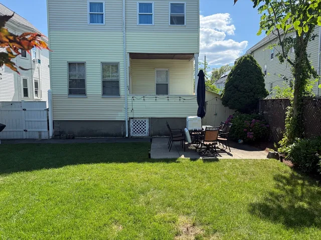 a view of a chair and table in backyard of the house