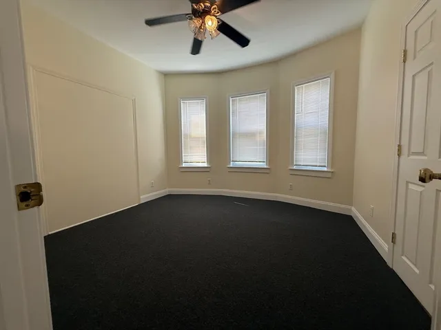 an empty room with a window and ceiling fan