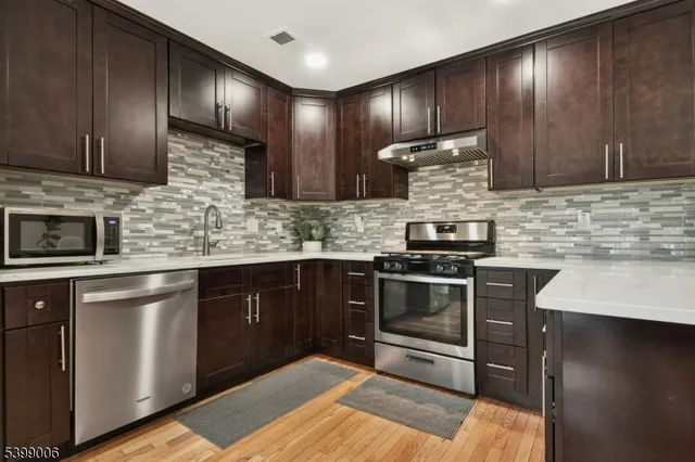 a kitchen with stainless steel appliances granite countertop wooden cabinets a stove top oven a sink and dishwasher