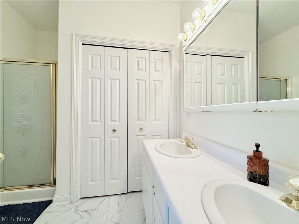 603 South Raccoon Road, Unit 1 Austintown, OH 44515 - Photo 13 of 22 Bathroom featuring a dual vanity with integrated sinks, a built-in medicine cabinet, a shower enclosure with a gold-tone frame, and bifold paneled doors