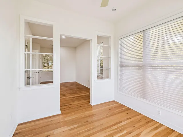 a view of an empty room with wooden floor and a window