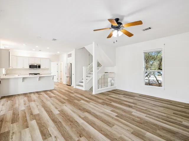 a view of an empty room with window and wooden floor