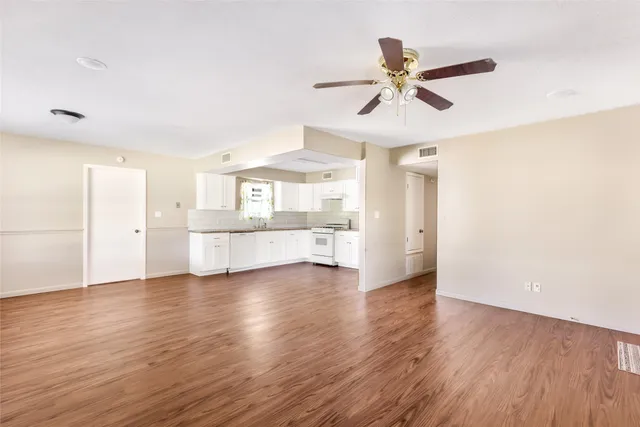 a view of an empty room with window and wooden floor