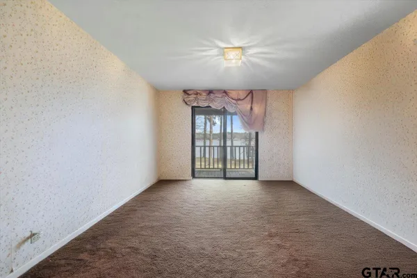 an empty room with chandelier fan and windows