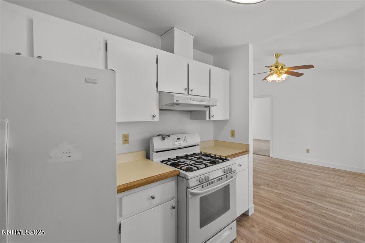 4830 Rampion Way Sun Valley, NV 89433 - Photo 7 of 30 a kitchen with granite countertop a stove a sink and dishwasher with white cabinets