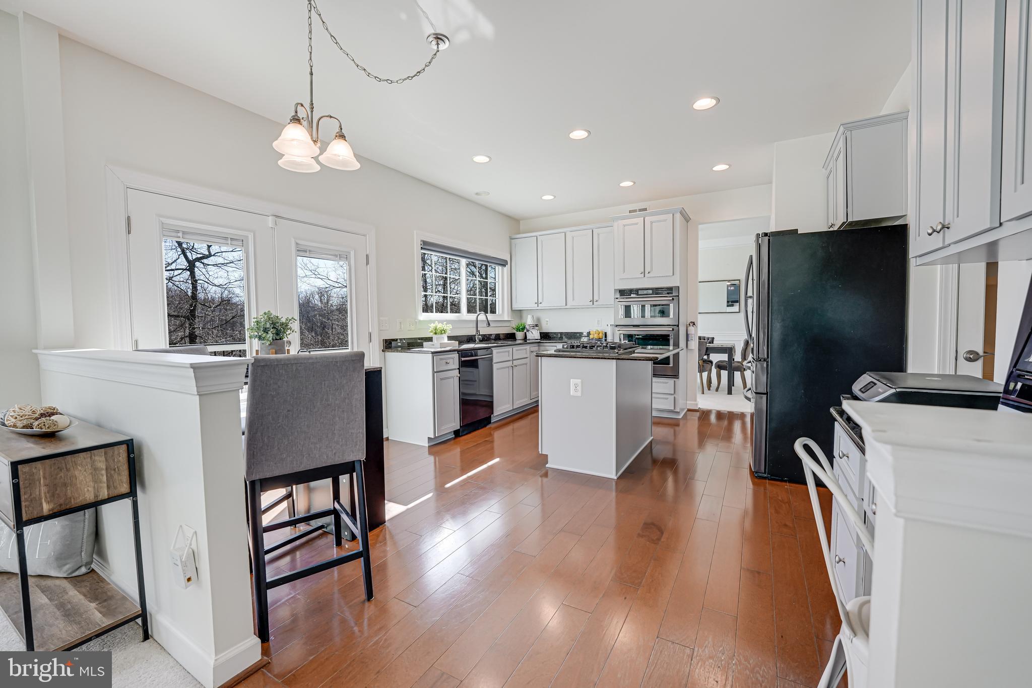 17583 Summer Duck Drive Dumfries, VA 22026 - Photo 17 of 49 a kitchen with stainless steel appliances granite countertop a refrigerator a stove top oven a sink dishwasher a dining table and chairs with wooden floor