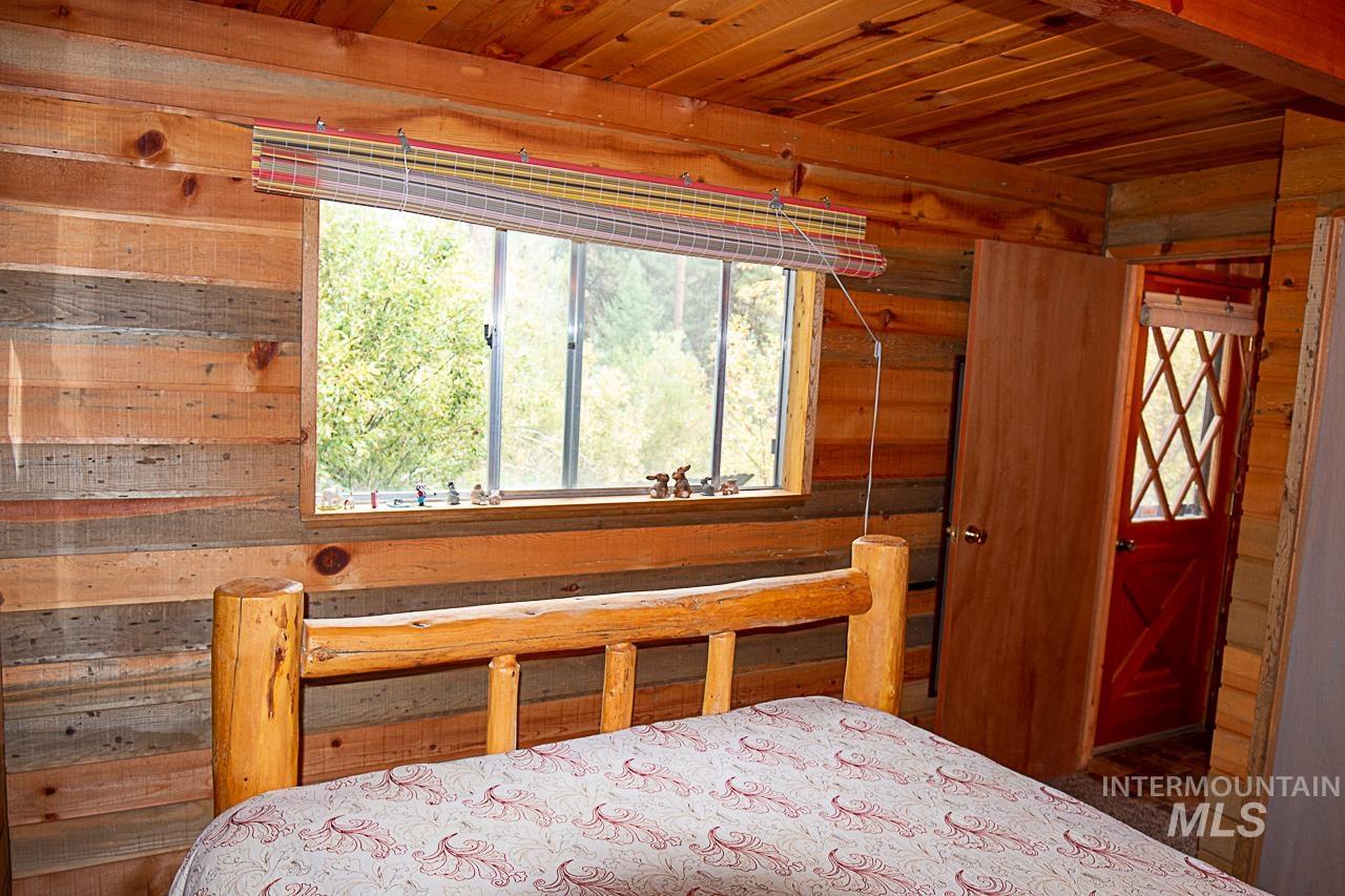 225 Mesplie Road Placerville, ID 83666 - Photo 11 of 39 Bedroom with wooden ceiling and wooden walls