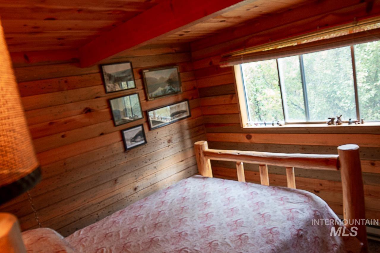 225 Mesplie Road Placerville, ID 83666 - Photo 22 of 39 Bedroom featuring wooden walls and a wooden ceiling with exposed beams