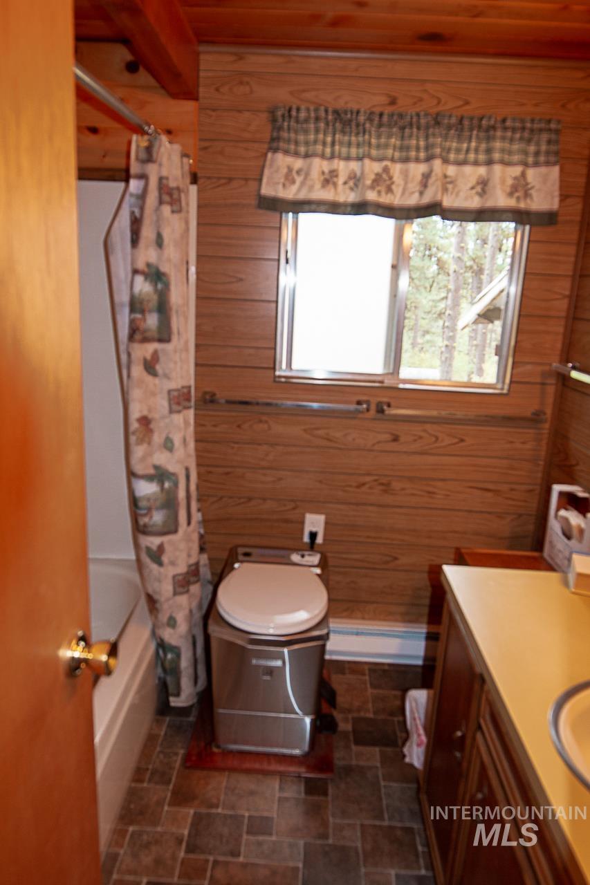 225 Mesplie Road Placerville, ID 83666 - Photo 23 of 39 Full bathroom featuring wooden walls, vanity, shower / bath combination with curtain, stone finish flooring, and wooden ceiling