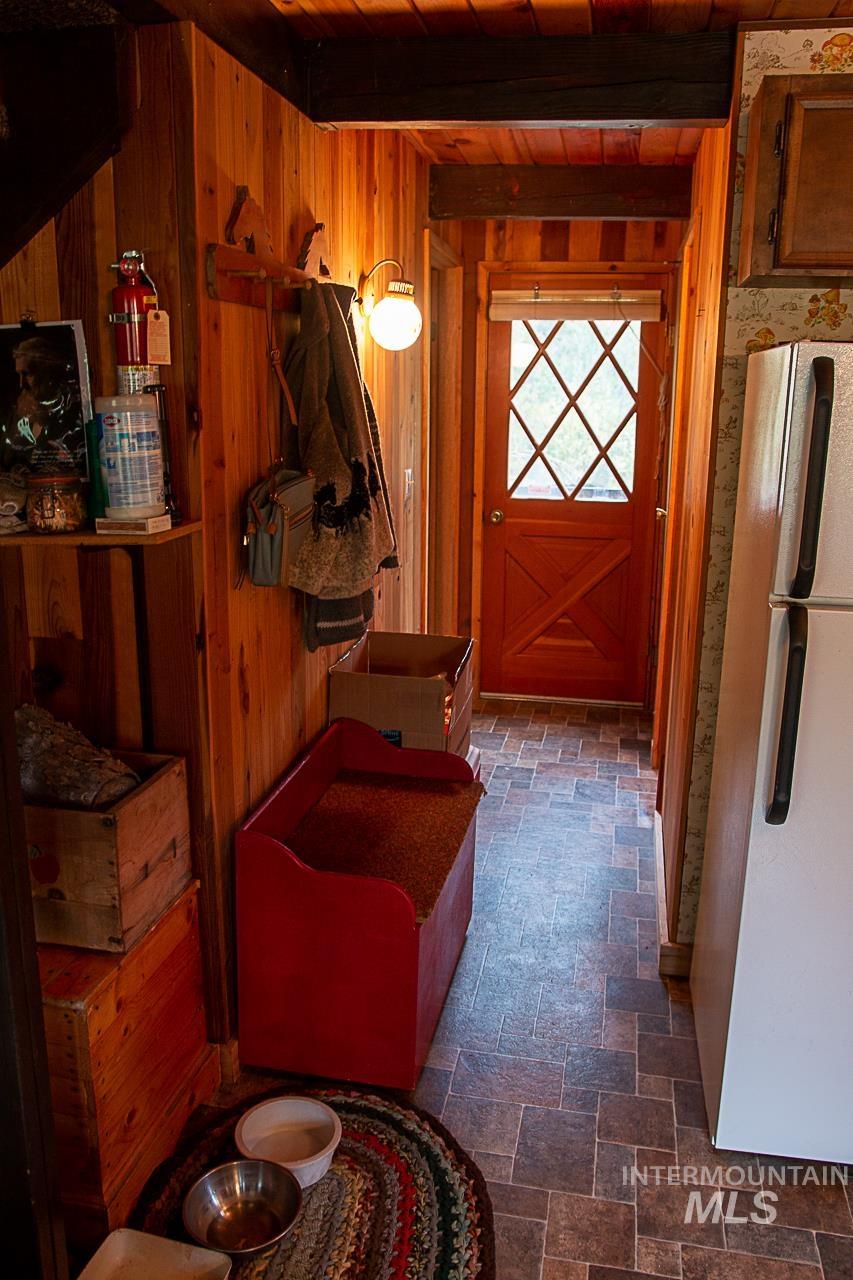 225 Mesplie Road Placerville, ID 83666 - Photo 30 of 39 Hall with a wood ceiling with exposed beams, dark stone finish flooring, and wood walls