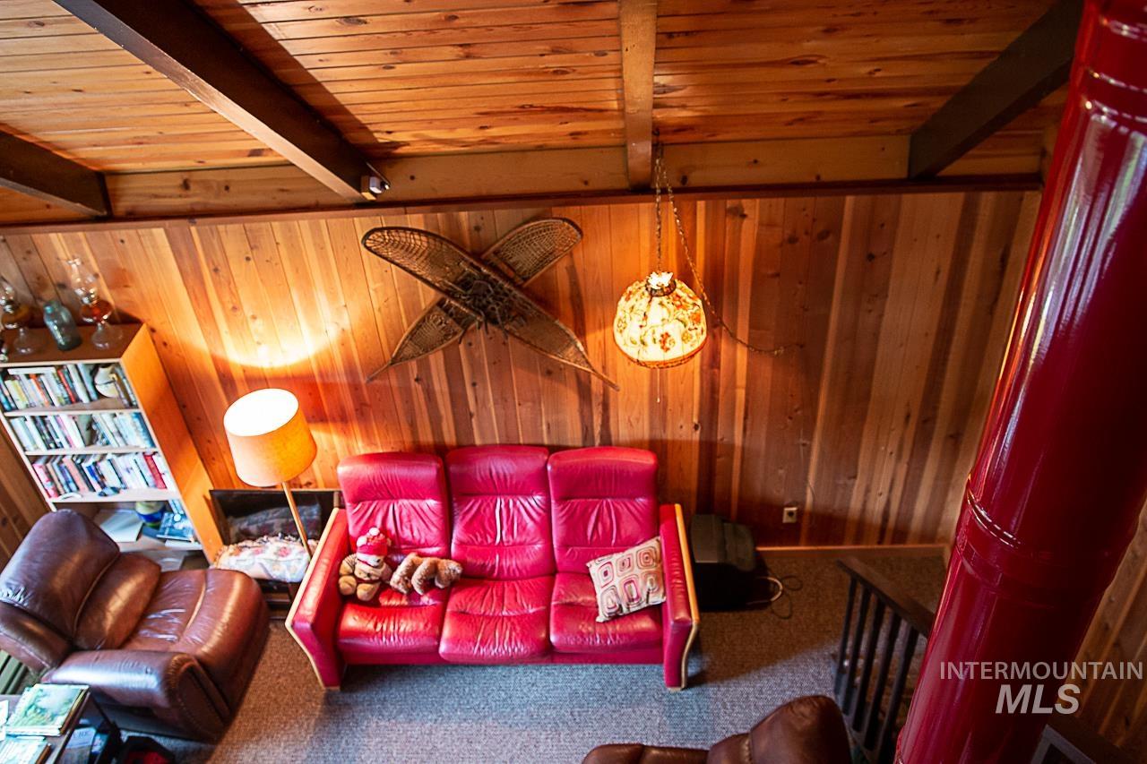 225 Mesplie Road Placerville, ID 83666 - Photo 31 of 39 Carpeted living area with wooden walls and a wood ceiling with exposed beams