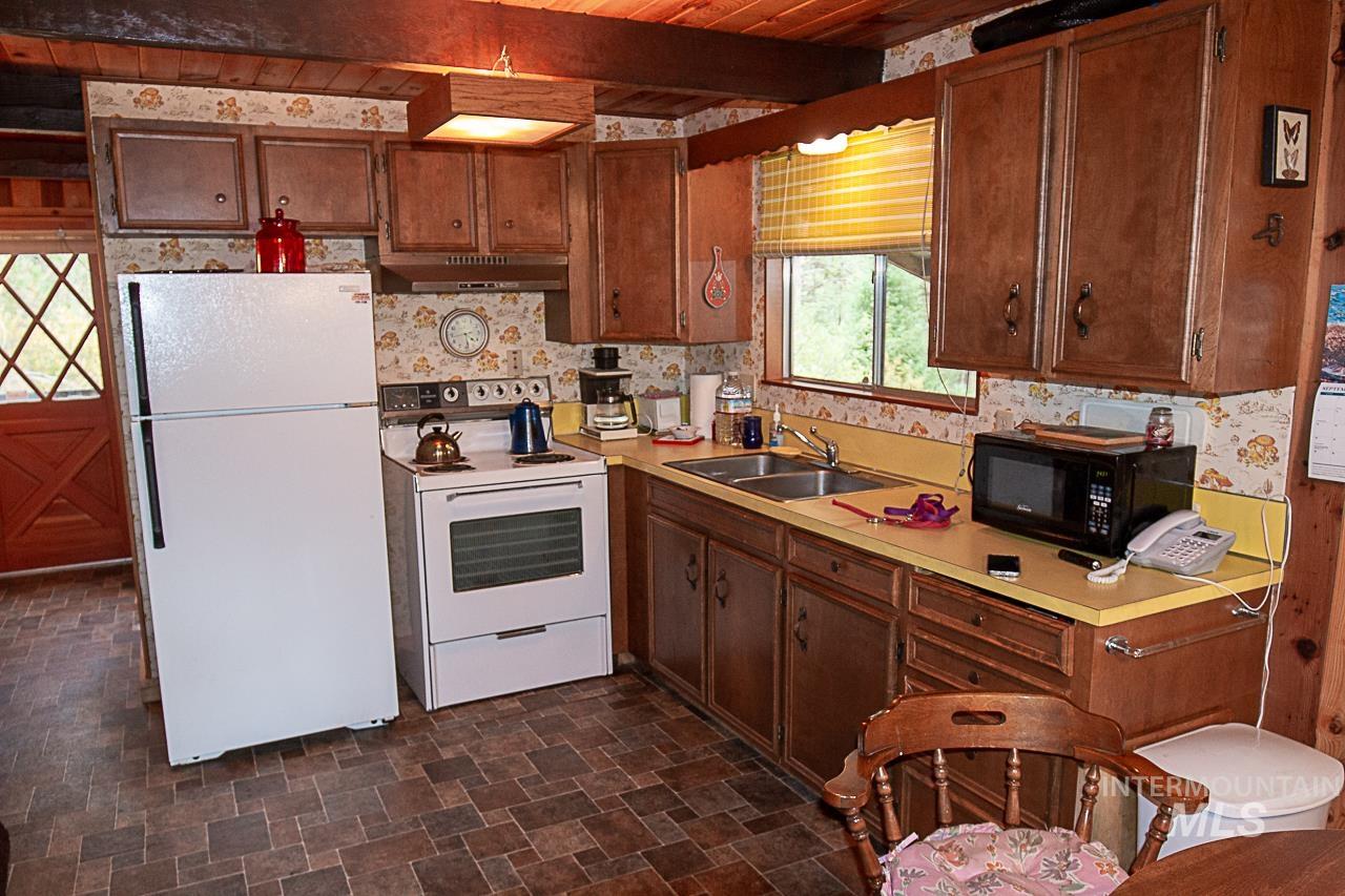 225 Mesplie Road Placerville, ID 83666 - Photo 7 of 39 Kitchen featuring white appliances, light countertops, a wood ceiling with exposed beams, and under cabinet range hood