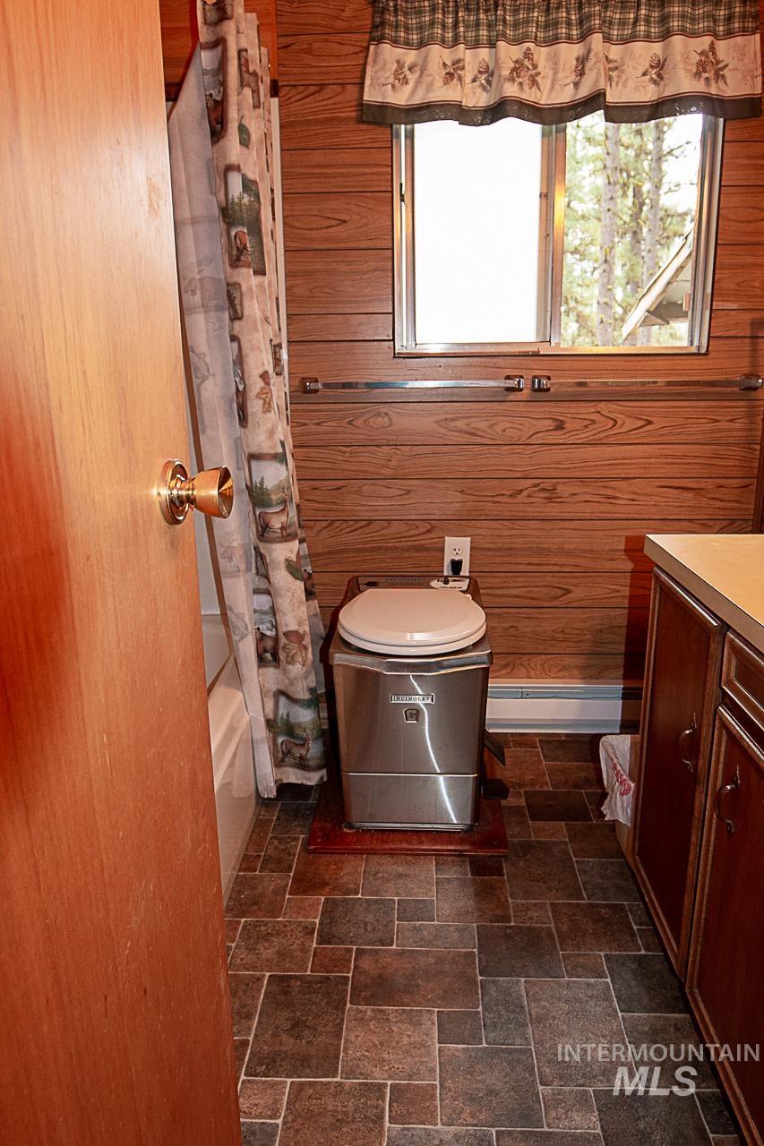 225 Mesplie Road Placerville, ID 83666 - Photo 9 of 39 Full bath featuring wood walls, healthy amount of natural light, stone tile flooring, and vanity