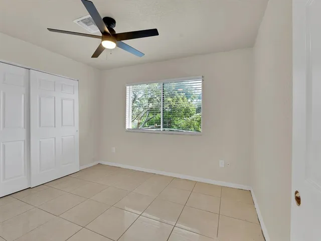 an empty room with a ceiling fan and window