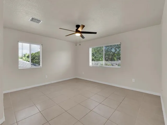 an empty room with windows and ceiling fan