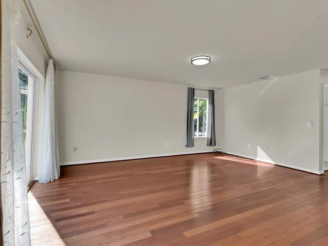 a view of an empty room with wooden floor and window