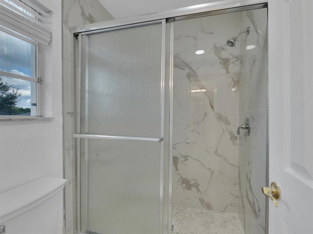 308 Northwest 17th Terrace Pompano Beach, FL 33069 - Photo 10 of 43 a bathroom with a glass shower door