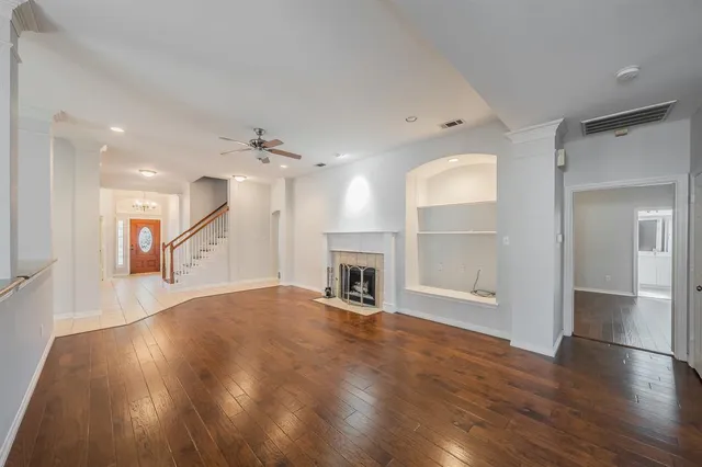 an empty room with wooden floor and a kitchen