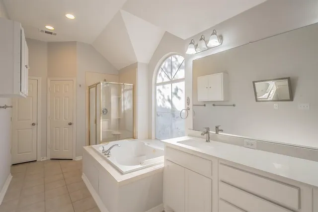 a bathroom with a tub a sink and a large mirror