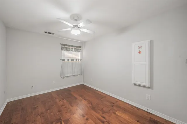 an empty room with a window and wooden floor