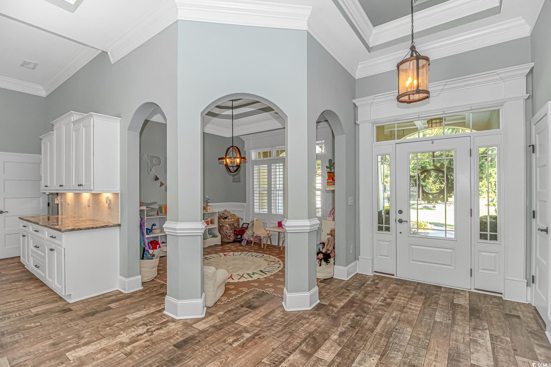 4383 River Road Little River, SC 29566 - Photo 6 of 40 Foyer entrance featuring ornamental molding, arched walkways, a chandelier, dark wood-style floors, and a towering ceiling