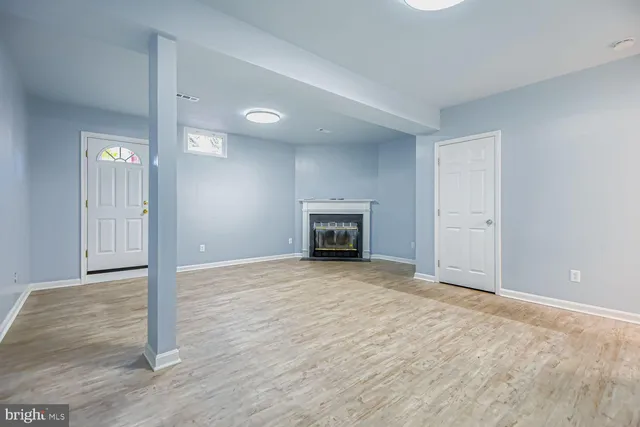 a view of empty room with wooden floor and fireplace